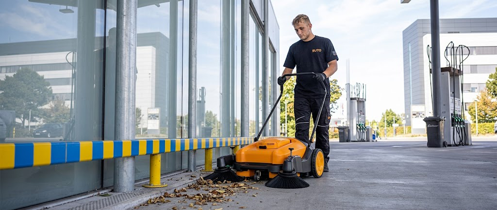 A man is pushing a sutoclean manual sweeper
